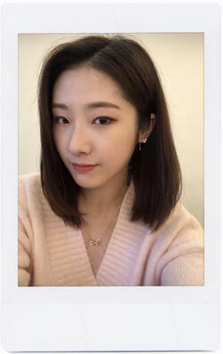 a haseul selfie, with her wearing a pastel pink sweater